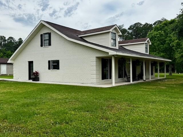 view of property exterior with a lawn, brick siding, and a patio area
