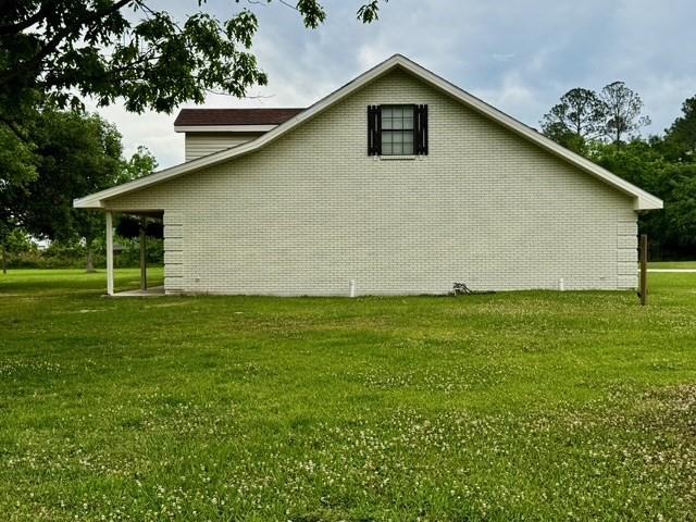 view of side of home featuring a yard and brick siding