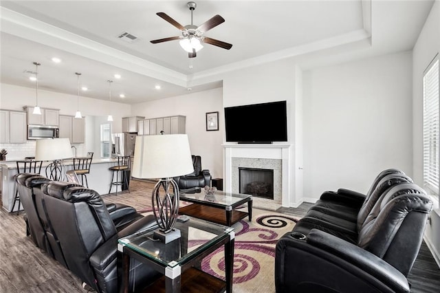 living room featuring a premium fireplace, a ceiling fan, recessed lighting, wood finished floors, and visible vents