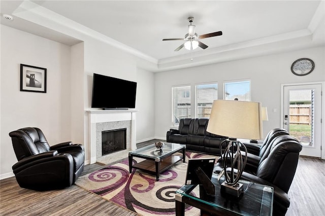 living room featuring ceiling fan, a healthy amount of sunlight, a raised ceiling, and wood finished floors