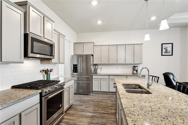 kitchen featuring decorative backsplash, high end appliances, a sink, gray cabinetry, and dark wood-type flooring