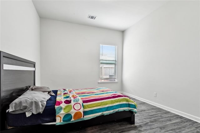bedroom featuring visible vents, baseboards, and wood finished floors