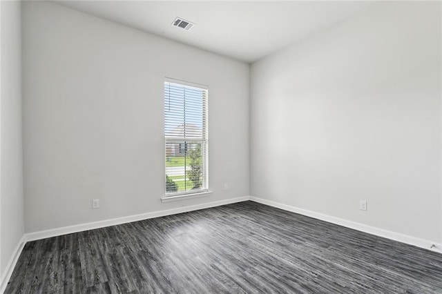 spare room with baseboards, visible vents, and dark wood-style floors