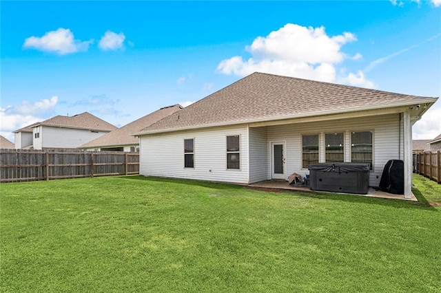 rear view of property with a hot tub, a lawn, a fenced backyard, and roof with shingles