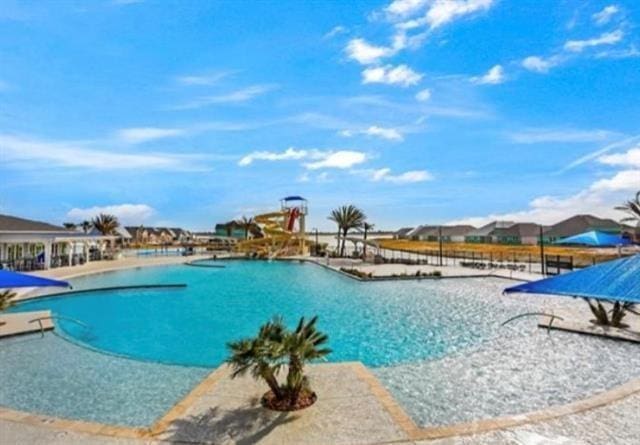 pool with a water slide, a patio area, and a water play area