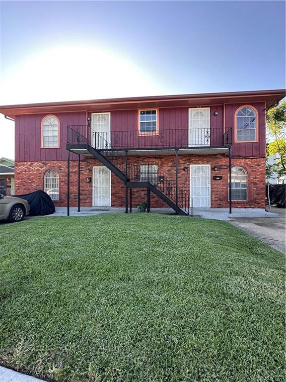 view of front of home with stairs, a front lawn, and brick siding