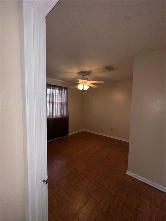 empty room with baseboards, a ceiling fan, and visible vents