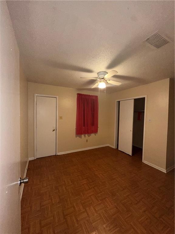 spare room featuring visible vents, a textured ceiling, ceiling fan, and baseboards