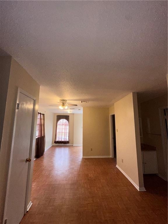 interior space featuring baseboards, a ceiling fan, and a textured ceiling