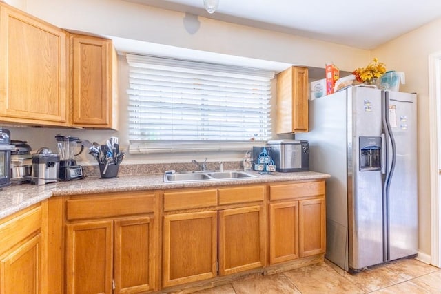 kitchen featuring brown cabinets, light tile patterned floors, stainless steel fridge with ice dispenser, a sink, and light countertops