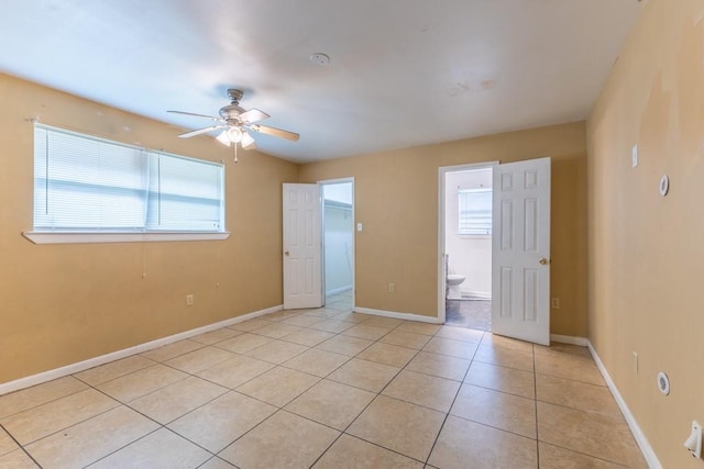 empty room featuring a healthy amount of sunlight, light tile patterned floors, baseboards, and a ceiling fan