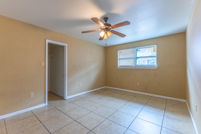 empty room featuring baseboards, a ceiling fan, and light tile patterned floors