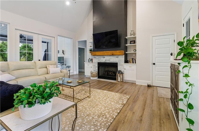 living area with high vaulted ceiling, baseboards, a fireplace, and wood finished floors