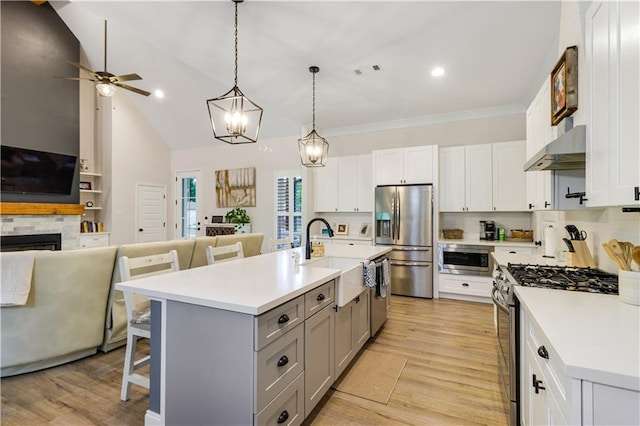 kitchen featuring gray cabinetry, open floor plan, appliances with stainless steel finishes, and range hood