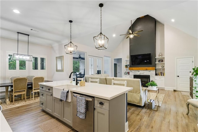 kitchen with a healthy amount of sunlight, stainless steel dishwasher, gray cabinetry, a sink, and ceiling fan with notable chandelier