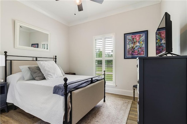bedroom featuring baseboards, ornamental molding, a ceiling fan, and wood finished floors