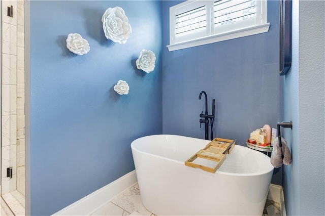 bathroom featuring baseboards, a soaking tub, and marble finish floor