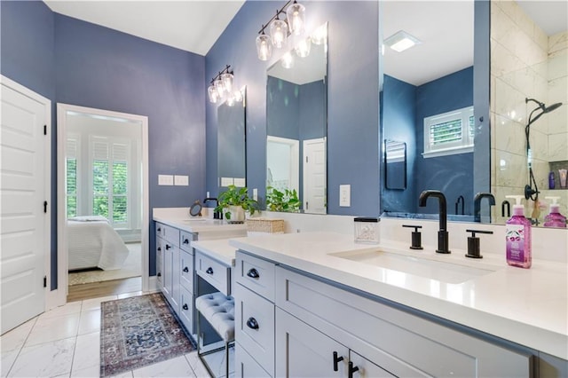 bathroom with double vanity, a sink, marble finish floor, and tiled shower