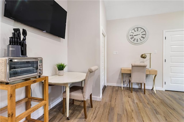 dining area featuring a toaster, baseboards, and light wood-type flooring