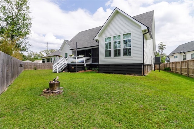 rear view of house featuring a fenced backyard, a wooden deck, and a yard