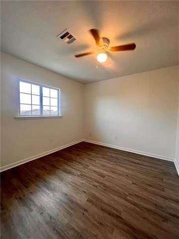 5227-5229 Cannes St, New Orleans, LA 70129 - spare room featuring baseboards, ceiling fan, dark wood finished floors, and visible vents