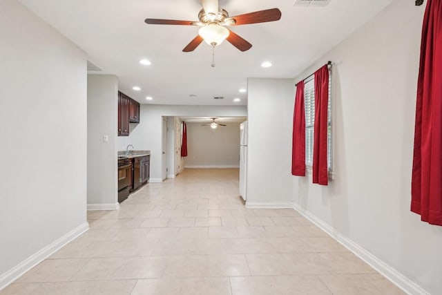 hall with visible vents, a sink, baseboards, light tile patterned floors, and recessed lighting