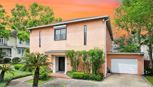 2100 Jefferson Ave, New Orleans, LA 70115 - view of front facade featuring stucco siding, concrete driveway, and a garage