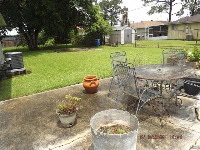 view of yard with a patio, central AC unit, outdoor dining area, a shed, and an outbuilding