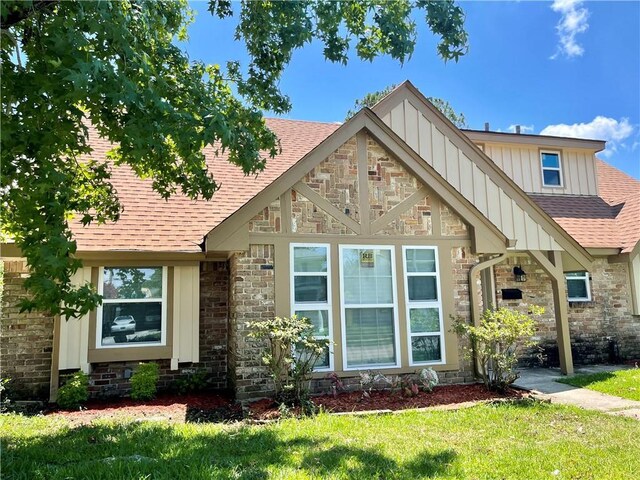 2644 Ramsey Dr, New Orleans, LA 70131 - view of front of property with a shingled roof, board and batten siding, a front yard, and stone siding