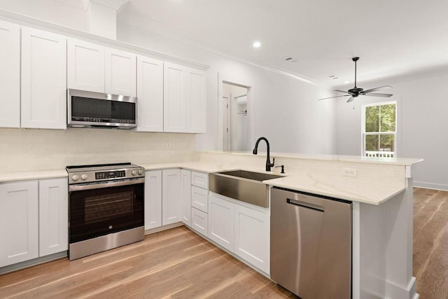 71131 Sanders St, Abita Springs, LA 70420 - kitchen with stainless steel appliances, a sink, a peninsula, light wood-style floors, and ceiling fan