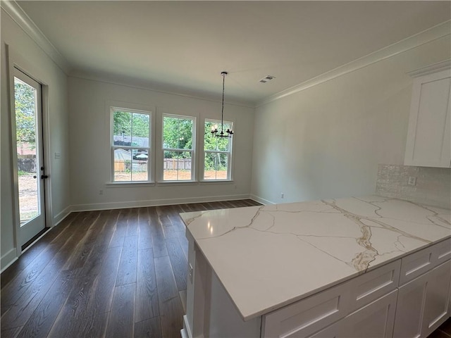 kitchen featuring light stone counters, white cabinets, an inviting chandelier, ornamental molding, and dark wood-type flooring