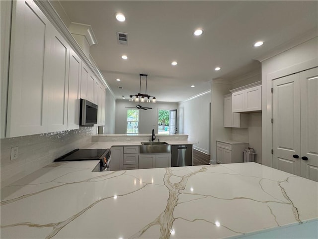 kitchen with visible vents, crown molding, a sink, a peninsula, and stainless steel appliances