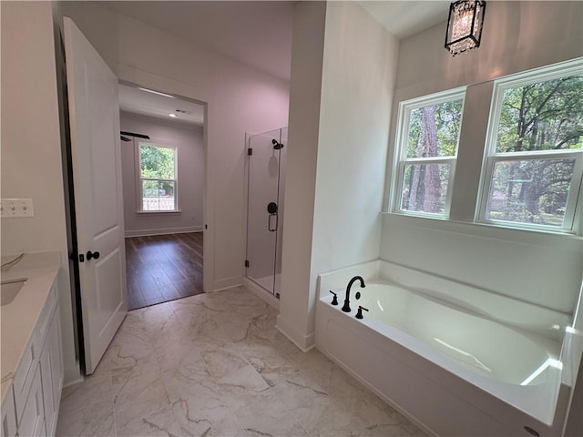 bathroom with a bath, a stall shower, vanity, baseboards, and marble finish floor