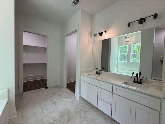 bathroom with a sink, a garden tub, marble finish floor, and visible vents