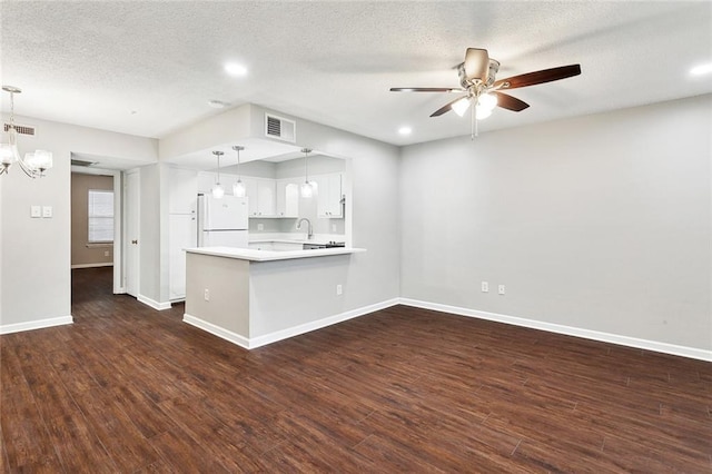 kitchen with visible vents, light countertops, freestanding refrigerator, ceiling fan with notable chandelier, and a peninsula