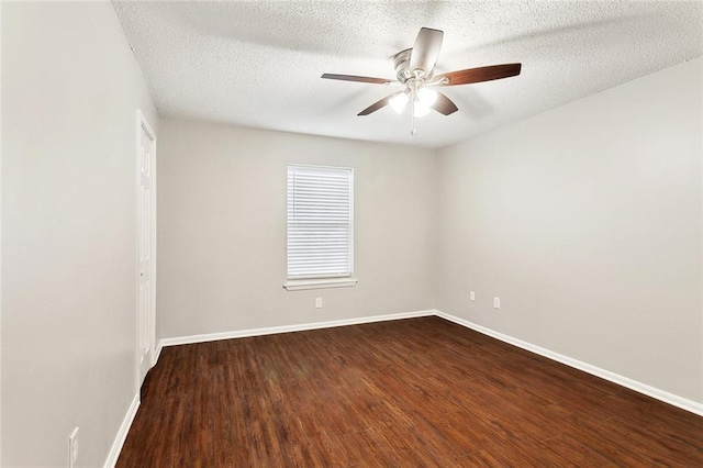 spare room featuring a textured ceiling, ceiling fan, dark wood finished floors, and baseboards
