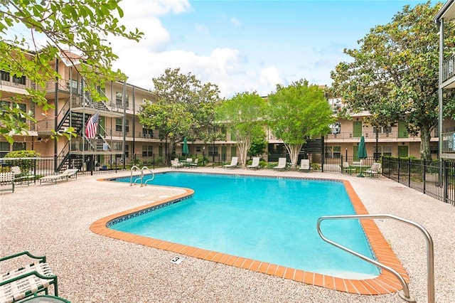 community pool with fence and a patio area