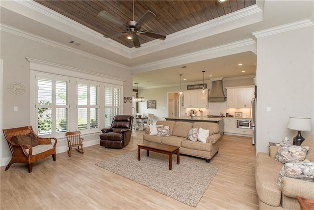 living room with light wood-style floors, a raised ceiling, and ceiling fan