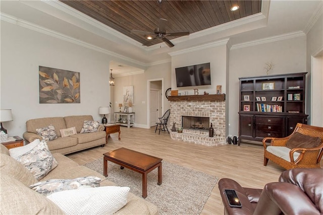 living room featuring wood finished floors, a fireplace, baseboards, a raised ceiling, and a ceiling fan