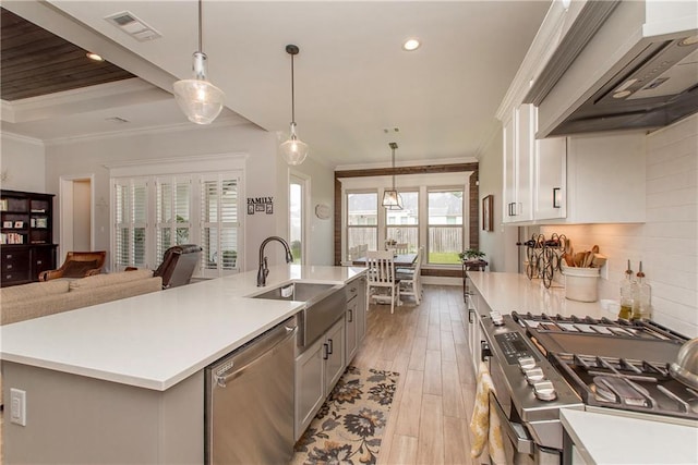 kitchen with appliances with stainless steel finishes, premium range hood, ornamental molding, and visible vents