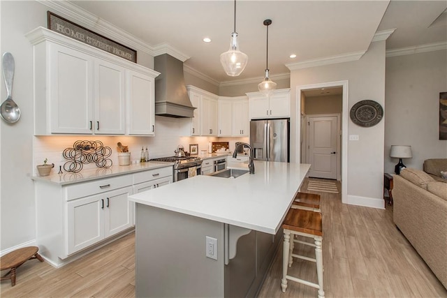 kitchen with a kitchen breakfast bar, wall chimney range hood, recessed lighting, a sink, and appliances with stainless steel finishes