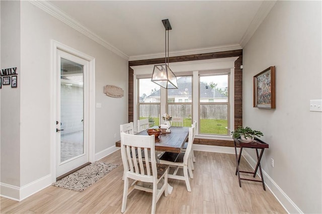 dining room with baseboards, ornamental molding, and light wood finished floors