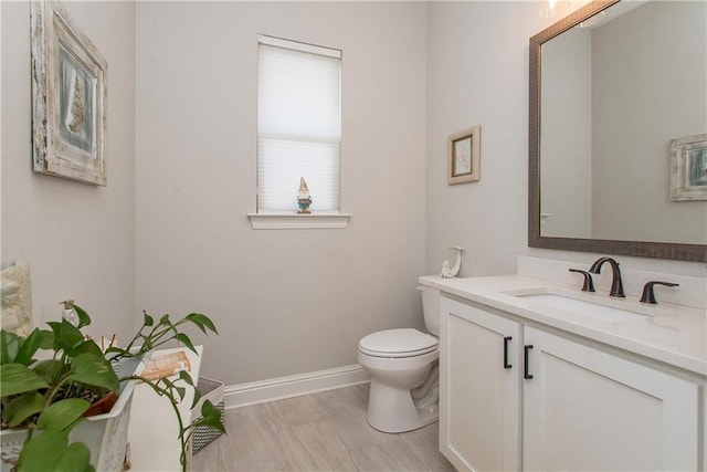 half bath featuring vanity, baseboards, and toilet