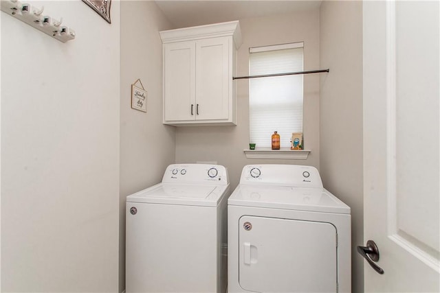 clothes washing area featuring cabinet space and washer and clothes dryer