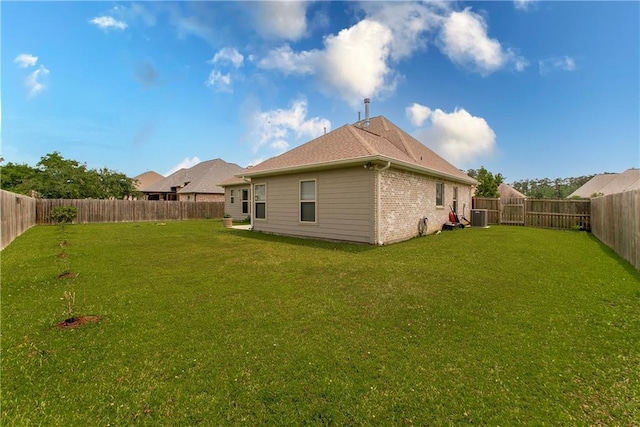back of property featuring a yard, central AC unit, and a fenced backyard
