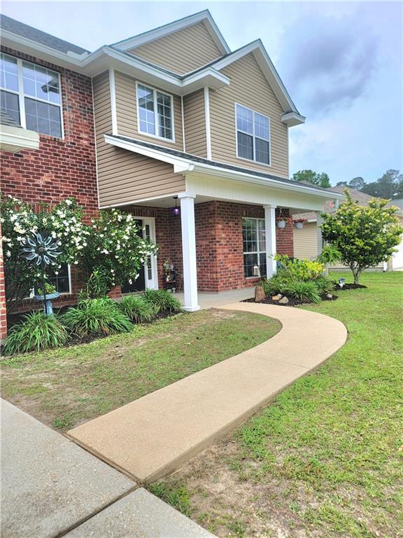 view of front of house featuring covered porch, brick siding, and a front yard