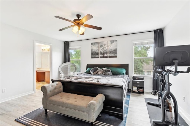 bedroom featuring a ceiling fan, multiple windows, light wood finished floors, and ensuite bath