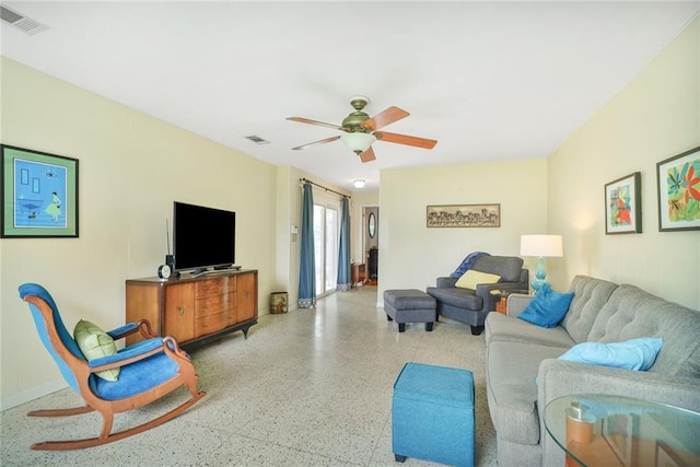 living area featuring speckled floor, visible vents, and ceiling fan