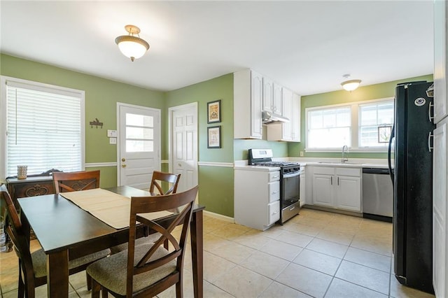 kitchen with a sink, freestanding refrigerator, dishwasher, under cabinet range hood, and gas range