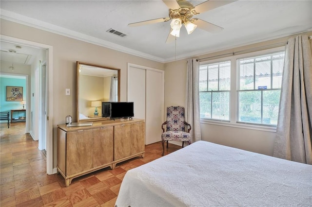 bedroom with a ceiling fan, a closet, attic access, visible vents, and crown molding